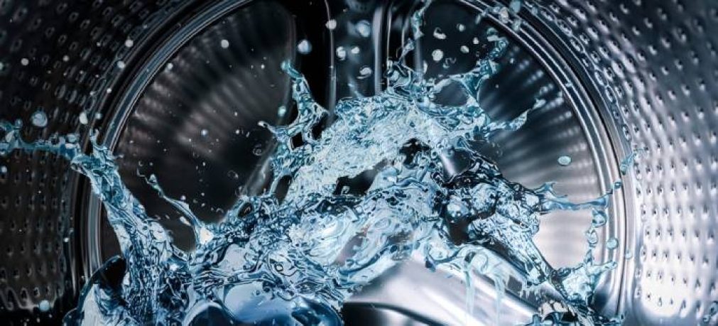 Washing machine drum with clean water flow and splashes. Laundry, washing powder concept.