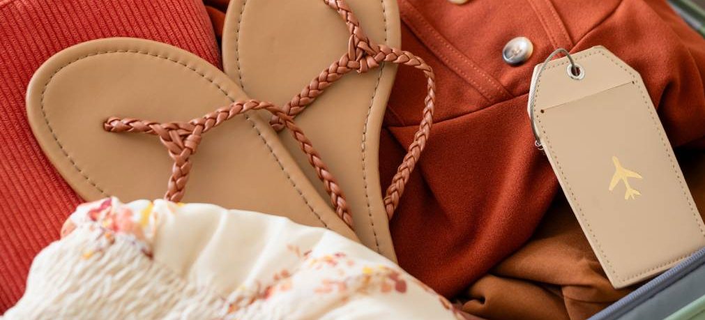 Close up of suitcase with sandals, hat, and floral clothing